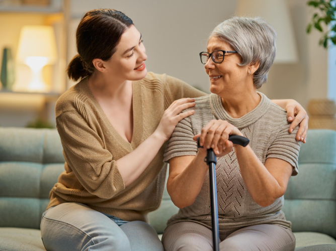 Happy patient and caregiver spending time together. Senior woman holding cane.